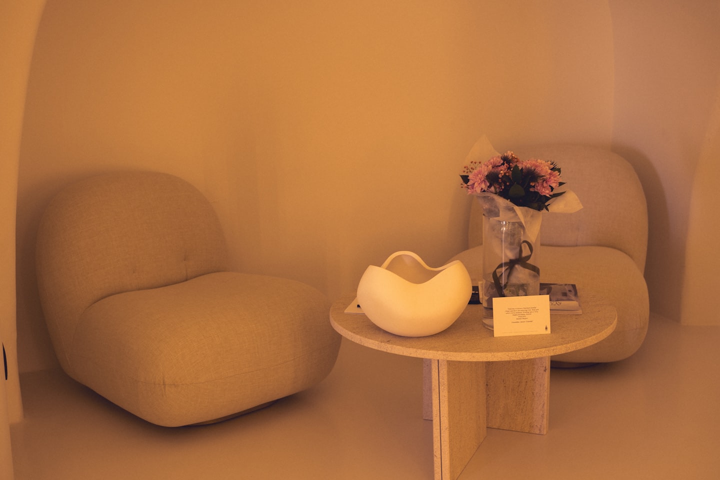 Zwei beige Sessel umringen einen Steintisch mit frischen Blumen.