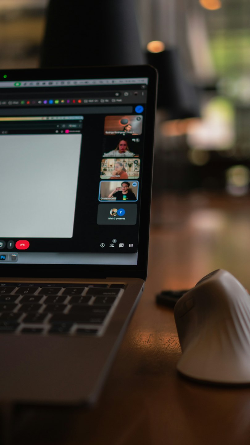 Laptop mit Videokonferenz auf einem Holztisch.